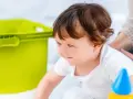 Mały poszukiwacz sensoryczny z zaciekawieniem odkrywa świat, obok niego zielony pojemnik i kolorowe zabawki.
