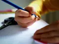 Dziecko pisze wzruszający list do taty. Na stole leżą nożyczki i kredki.