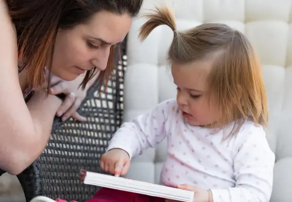 Mama czyta dziecku, a maluch odkrywa świat przez książkę, tworząc własne neologizmy dziecięce.